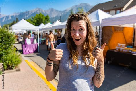 Portrait Of A Caucasian Girl With Brunette Hair And Tattooed Arms Giving Double Thumb Sign Of