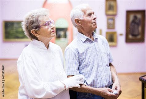 Mature European Couple Examines Paintings In An Exhibition In Hall Of Art Museum Stock Photo
