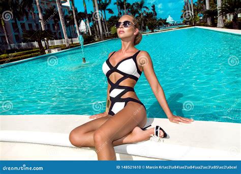 Elegant Woman In The White Bikini On The Sun Tanned Slim And Shapely Body Is Posing Near The