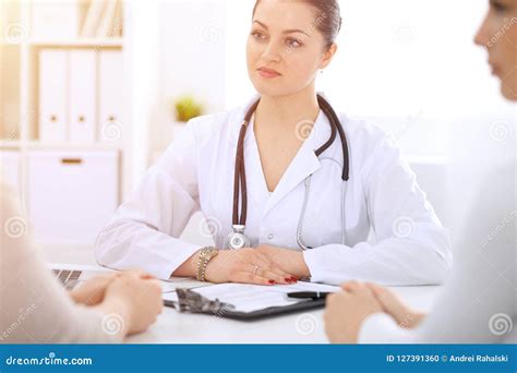 Brunette Female Doctor Talking To Patient At Hospital Office Physician Says About Medical Exams