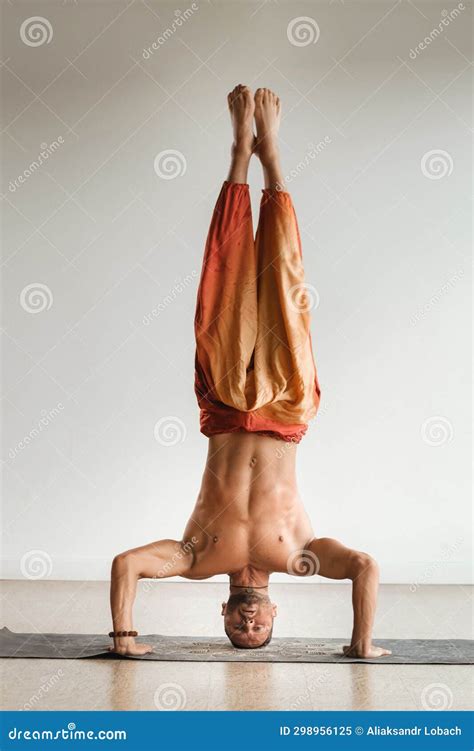 A Man With A Naked Torso Does Yoga Standing On His Head Indoors Fitness Trainer Stock Image