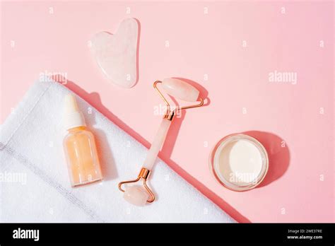 Cosmetic Serum Bottle Cream Jar And Face Roller Gua Sha Stone On Pink