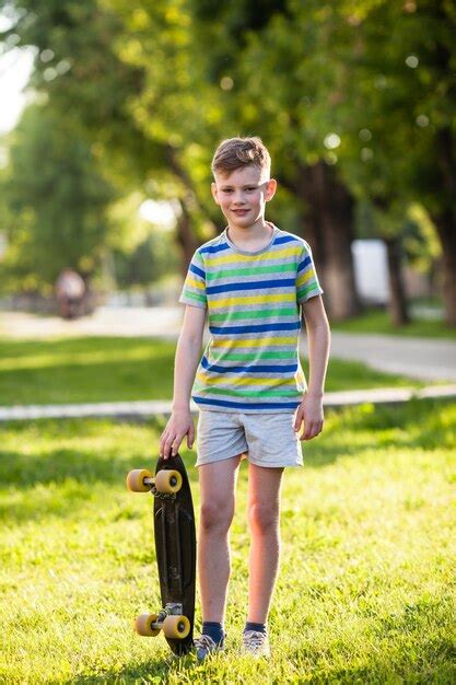 Niño en posición de cuclillas montando una patineta en el parque Foto