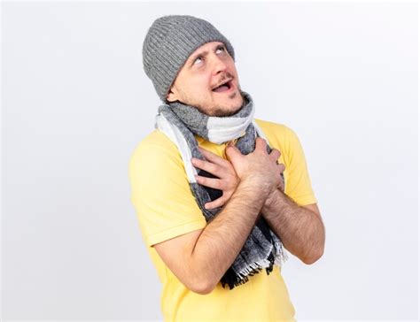Heureux jeune homme slave malade blonde portant un chapeau d hiver et une écharpe met les mains