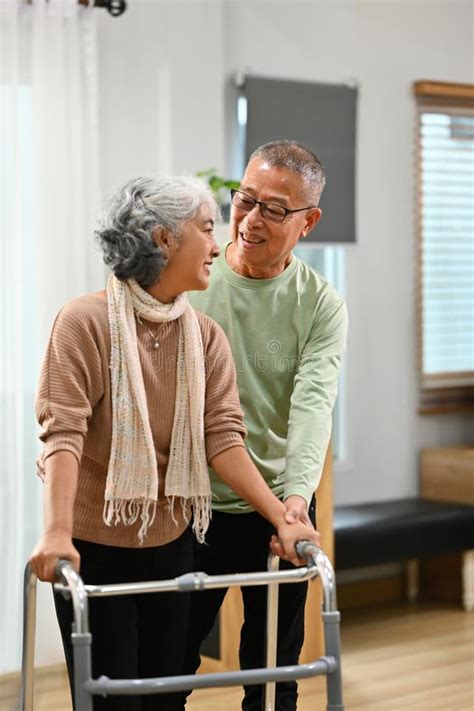 Caring Mature Man Helping His Wife Walking With Walker At Home Elderly Healthcare Concept Stock