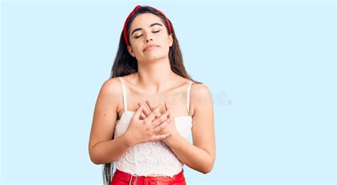 Una Adolescente De Brunette Con Una Apariencia Elegante Sonriendo Con Las Manos En El Pecho Con