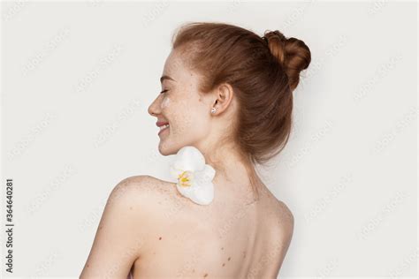 Back View Photo Of Naked Caucasian Woman With Freckles And Red Hair Holding A Flower On Her