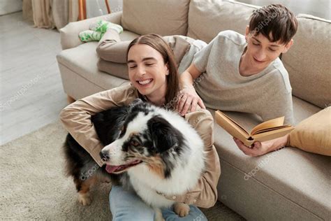 alegre gay hombre leyendo libro y descansando en cómodo sofá al lado de su novio con el pelo