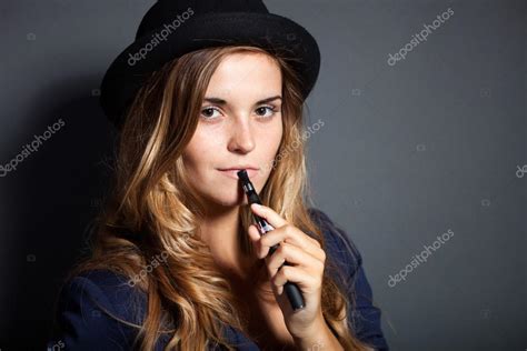 Elegant woman smoking e-cigarette wearing suit and hat — Stock Photo ...