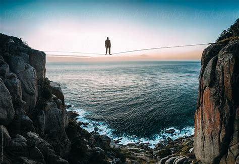 A Man Standing On A Tightrope Over The Sea By Stocksy Contributor