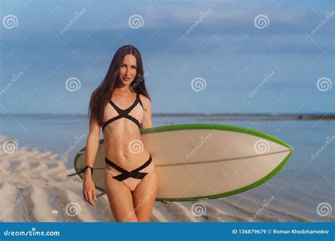 Beautiful Brunette Girl In Swimsuit Goes On Sandy Beach With Surfboard In Hand Stock Image