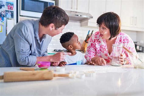 Happy Lesbian Couple And Son Baking Together In Kitchen Stock Photo