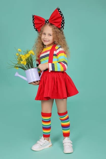 Premium Photo A Blonde Girl In A Skirt Knee Socks And A Tshirt With A Red Bow Holds A Bucket