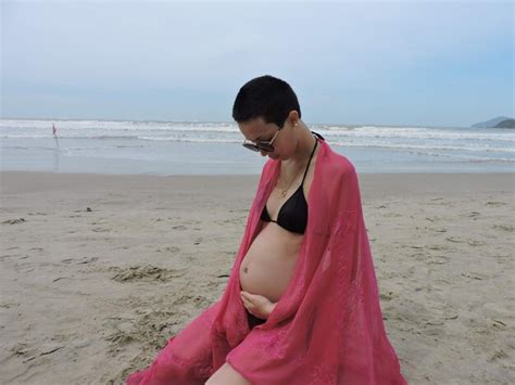 Mujer Embarazada Con Bikini Arrodillada En La Playa Contra El Cielo