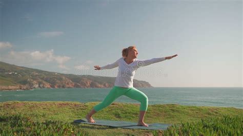 Senior Woman Practicing Yoga In Warrior Pose On Beach Stock Video