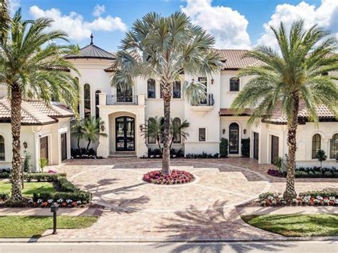 A Large White House With Palm Trees In The Front Yard