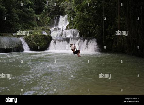 Full Length Of Shirtless Boy Swinging On Rope Over River At Forest