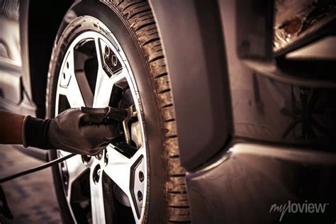 Auto Mechanic Checking Air Pressure And Inflating Car Tires Wall