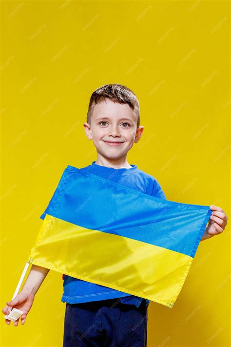 Premium Photo | Little boy smiling holding a yellow and blue flag