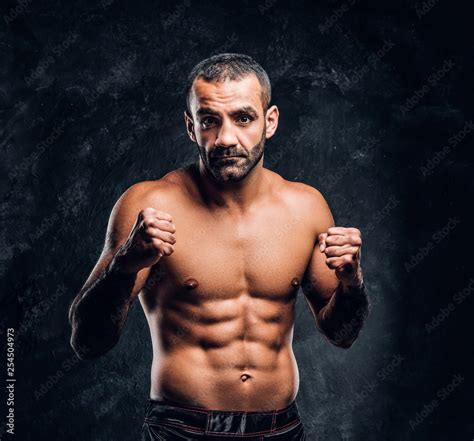 Professional Muay Thai Boxer With Naked Torso Posing For A Camera Studio Photo Against A Dark