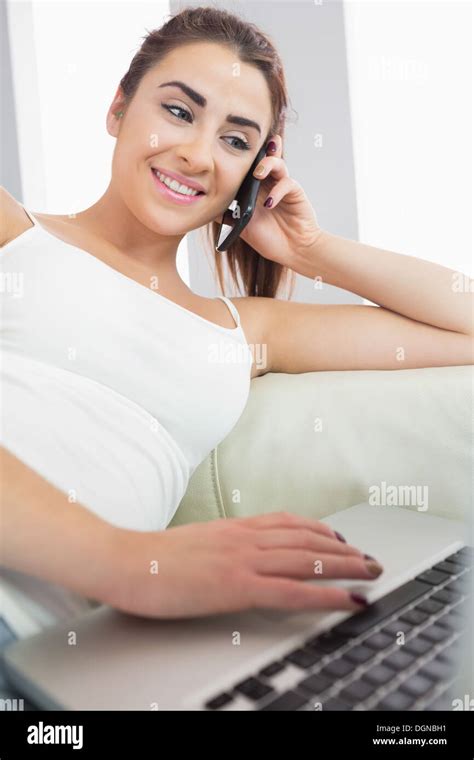 Smiling Pretty Brunette Woman Sitting In The Living Room Phoning Stock
