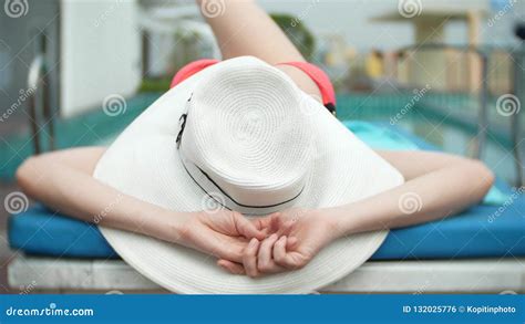 An Unrecognizable Slim Busty Woman In A Big White Hat And A Pink Bikini Is Lying On A Chaise