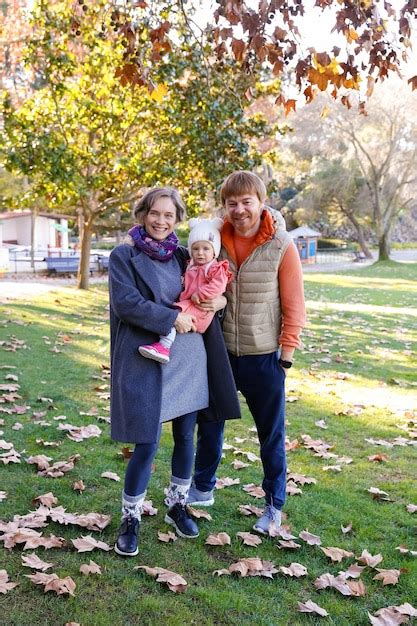 Retrato de familia feliz de pie en el parque otoño juntos y sonriendo