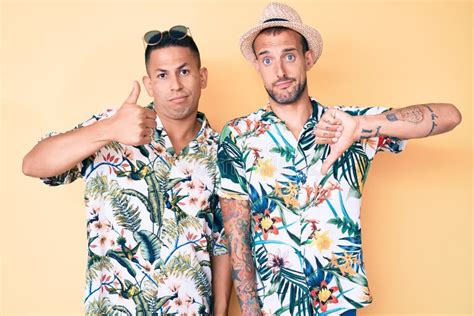 Joven Pareja Gay De Dos Hombres Con Sombrero De Verano Y Camiseta Hawaiana Haciendo El Pulgar