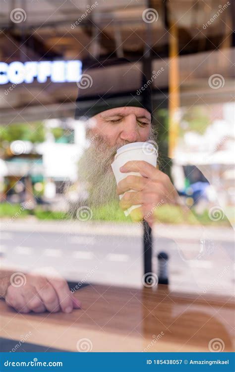 Mature Handsome Bearded Hipster Man Drinking Coffee At The Coffee Shop