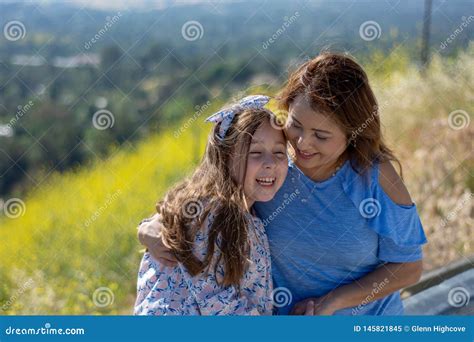 M E E Filha De Latina Que Sorriem E Que Riem Em Um Monte Na Frente Das Flores Amarelas Imagem De
