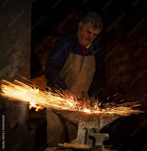 The Blacksmith Manually Forging The Hot Metal On The Anvil In Smithy With Spark Fireworks Stock