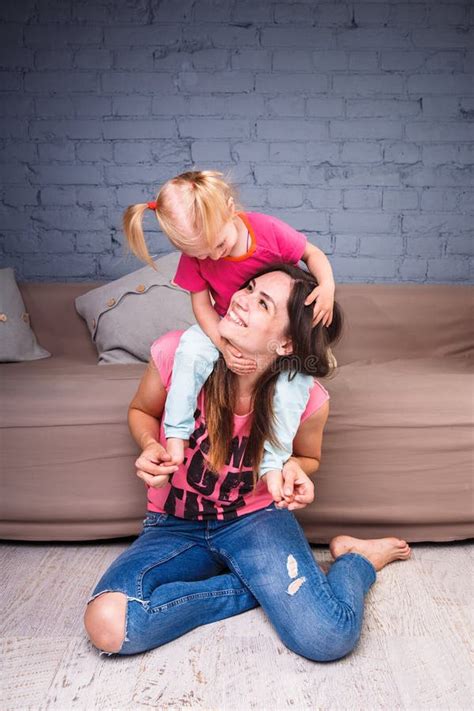 Une Jeune Belle Mère Mince Avec Sa Fille Blonde Sur Ses épaules Jouent Apprécient Et Se Livrent