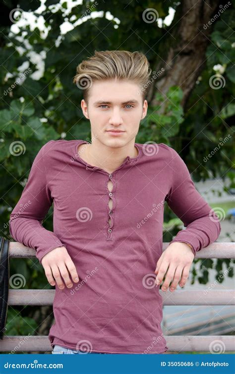 Knappe Blonde Jonge Mens Op Metaaltraliewerk Buiten Stock Foto Image Of Traliewerk Menselijk