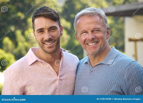 Portrait Of Laughing And Smiling Mature Father With Adult Son Standing Outdoors In Countryside