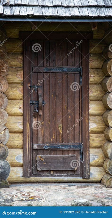 Brown Wooden Door In A Log Cabin With Wrought Iron Hinges And A Lock