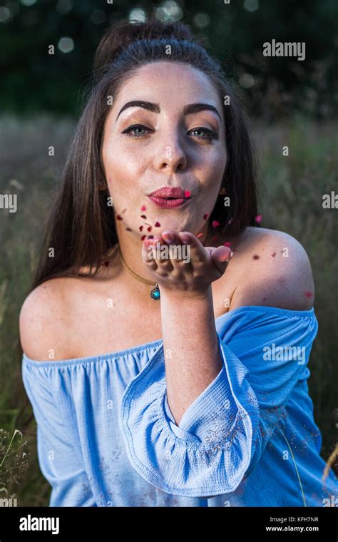 An Amateur Model In Her Mid Twenties Blows Red Hearts From Her Hand During A Portrait Shoot In A