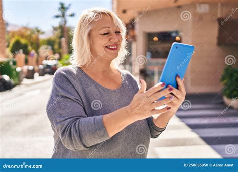 Middle Age Blonde Woman Smiling Confident Using Touchpad At Street Stock Photo Image Of Blonde