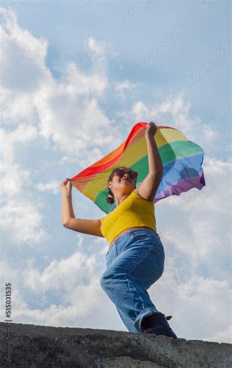 Mexican Teenager Waving Lgbt Gay Pride Flag On Blue Sky And Clouds Background Stock Photo