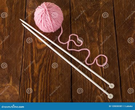 Skein Of Soft Pink Yarn And Knitting Needles On Wooden Surface Stock