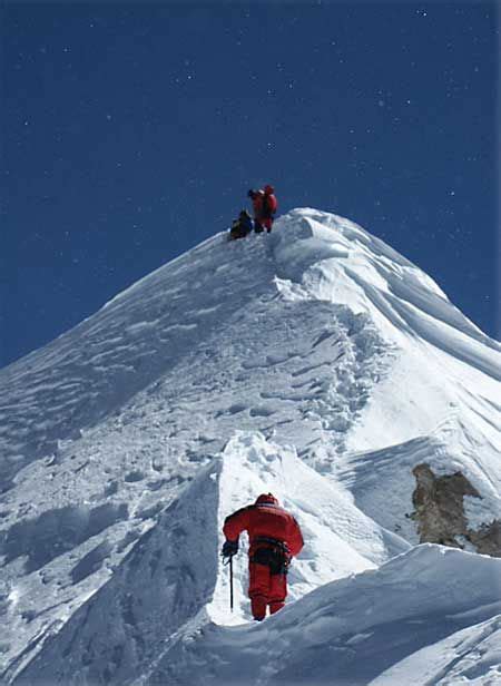 Two People Climbing Up The Side Of A Snow Covered Mountain