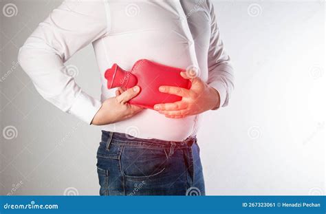 The Man Holds A Heating Pad With Hot Water On The Abdominal Wall On The Right Relieve Muscle