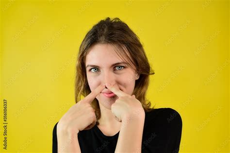 Close Up Studio Portrait Of A Pretty Blonde Girl In A Black T Shirt On A Yellow Background With