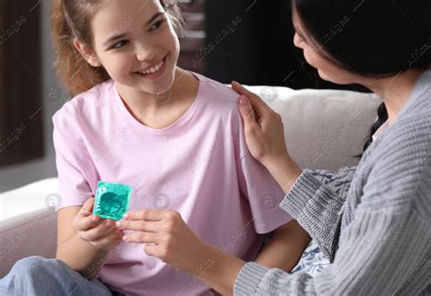 Mother Giving Condom To Her Teenage Daughter At Home Sex Education Concept Stock Photo