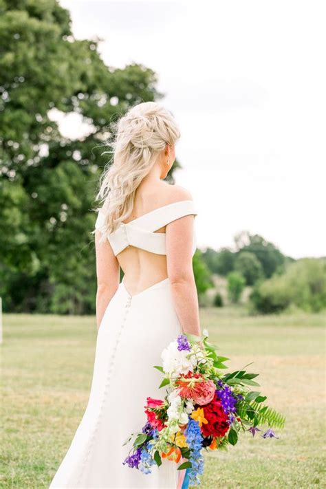 A Woman In A White Dress Is Holding A Colorful Bouquet And Looking At