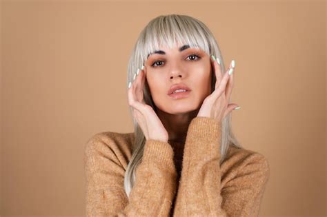 Fille Blonde Avec Une Frange Et Un Maquillage De Jour Marron Dans Un Pull Sur Fond Beige