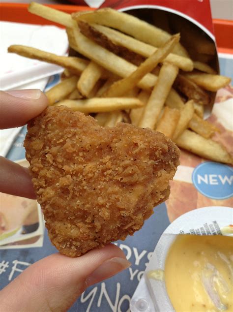 A Person Is Holding Up A Fried Chicken Nugget With Fries In Front Of Them