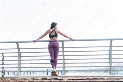 Beautiful Brunette Fitness Model Back To The Camera Wearing A Black Long Sleeve Top And Purple