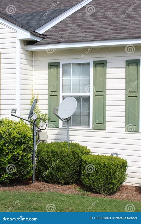 White And Green House Front With Two Satellite Dishes In The Front Yard