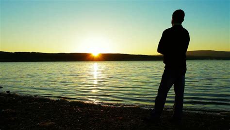 Young Man Praising And Worshiping God During Sunset By The Sea Stock