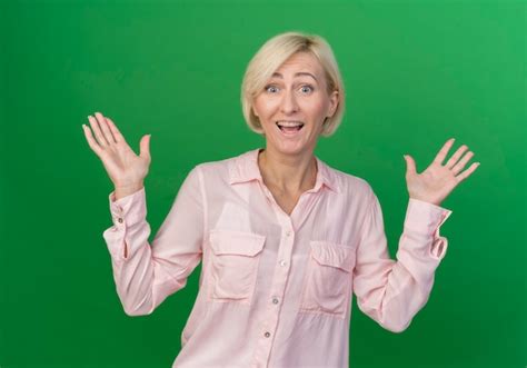 Impressionné jeune femme slave blonde montrant les mains vides isolé sur fond vert Photo Gratuite